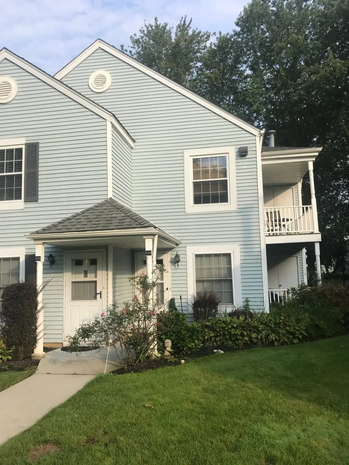 Selling a house with foundation problems in Middle Island: blue-sided townhouse with a small front porch