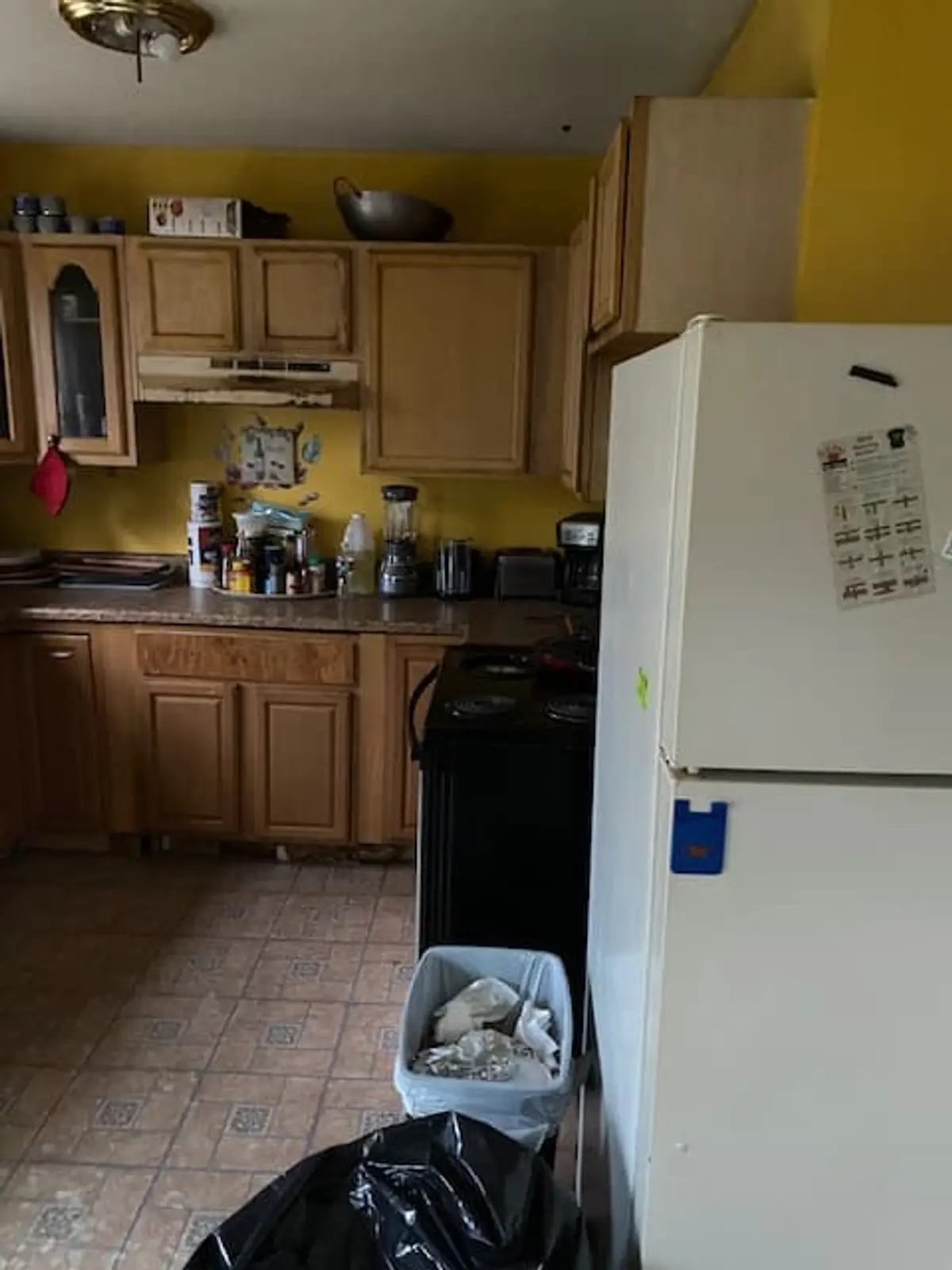 Selling a house during a divorce in Middle Island: kitchen with honey oak cabinets and a white fridge