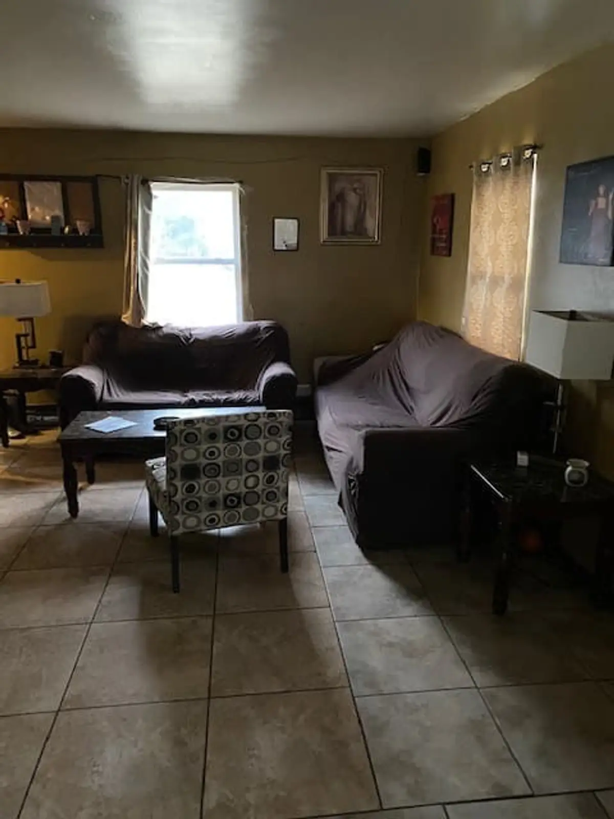 Wondering what your Middle Island house is worth: living room with tile floors and dark sofas